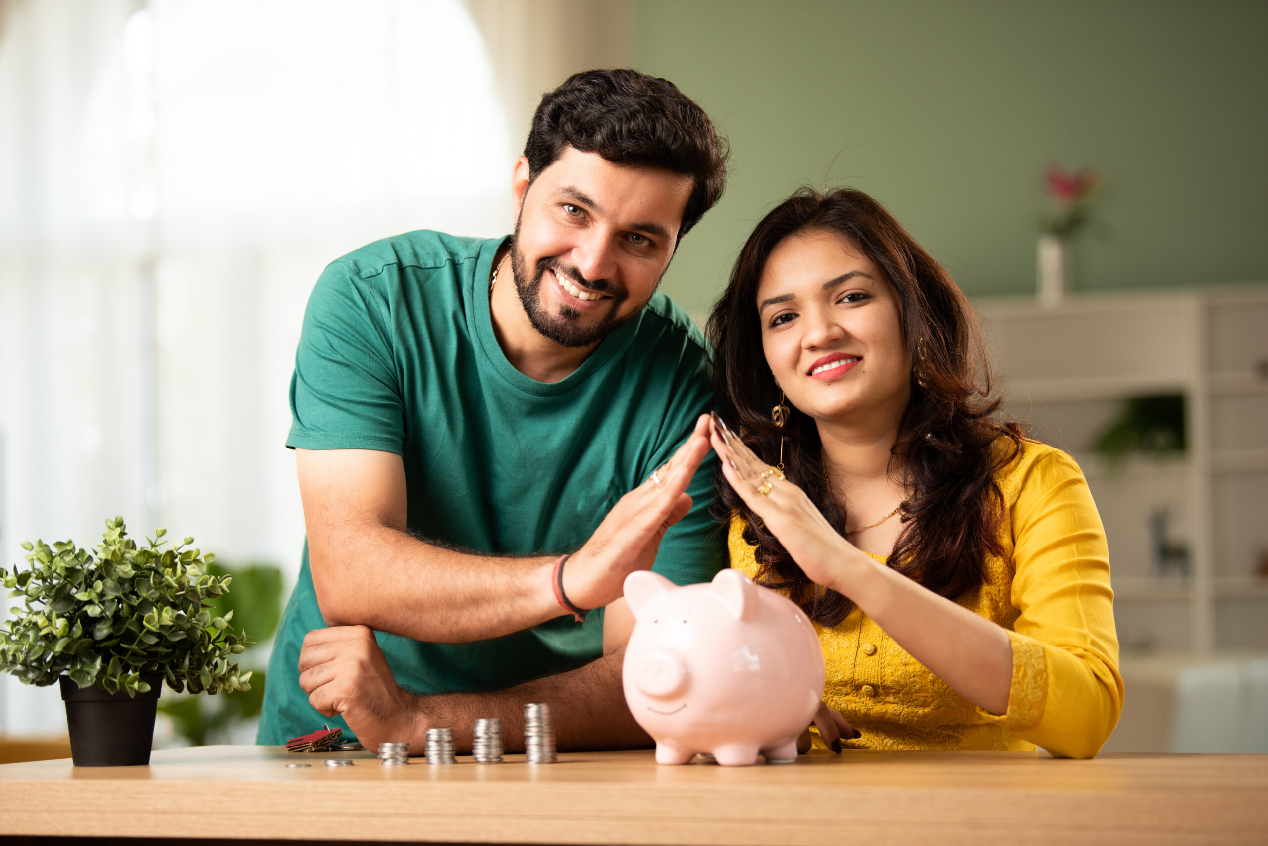 Indian couple saving money in piggy bank for home buying, showing great returns